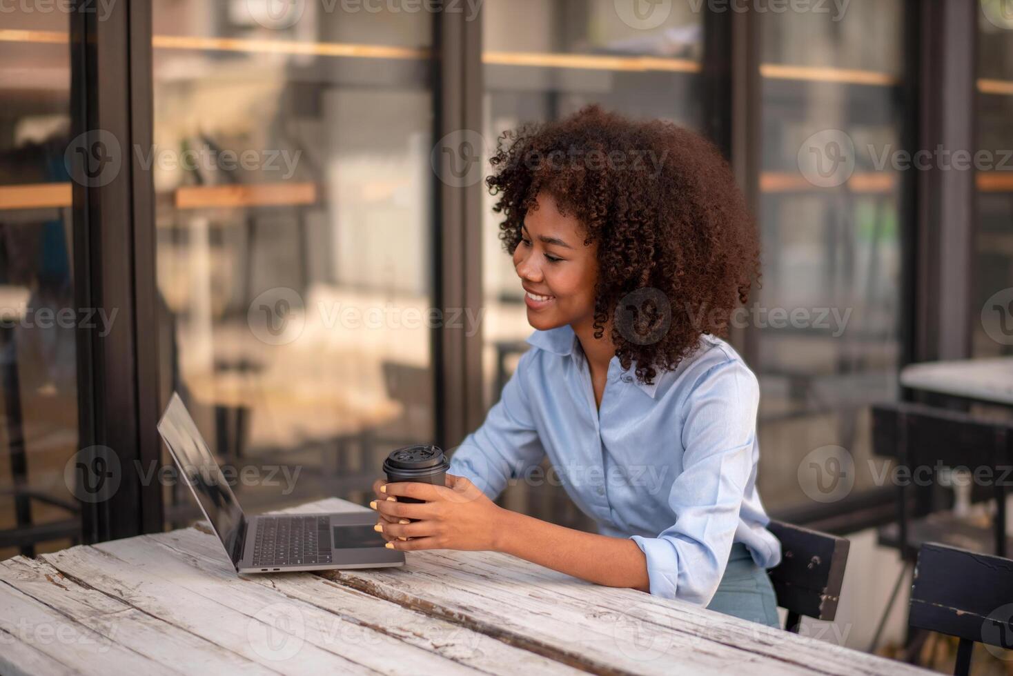 Black woman interested in something on computer screen Computer chatting, holding cup of coffee in hands socializing with friend photo