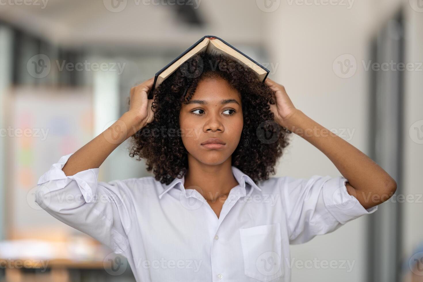 A young woman with a book turned face down on her head. look bored in reading photo