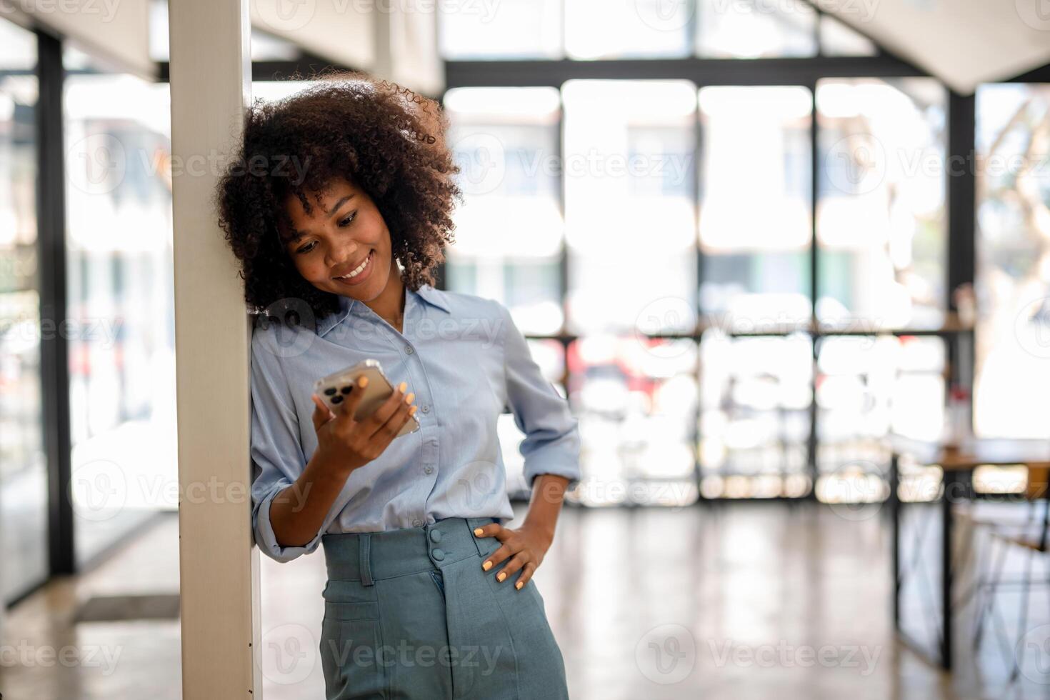 Portrait of smiling black woman with smart phone enjoys online surfs social networks photo