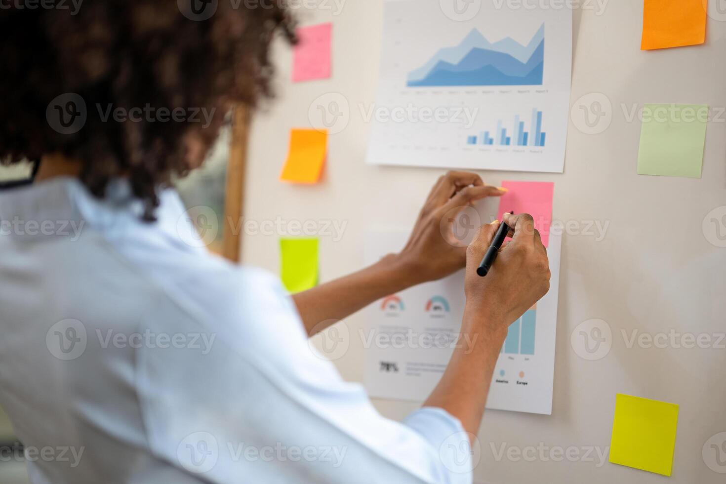 A hand that is about to write a message on the note paper pasted on the board. Plan your event by taking notes. Take note of important information. photo