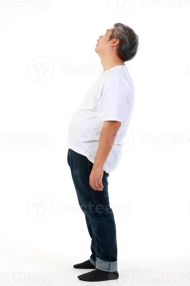 Fat Asian man wearing a white t-shirt. standing on a white background He felt uncomfortable, abdominal distension, and had symptoms of illness. Weight loss concept. Healthy health care. copy space photo