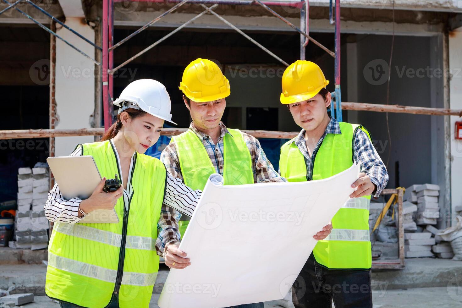 Architects and Engineers and Builders Holding a blueprint discussing building construction plans at the outdoor site. Real estate project concepts, building construction cooperation. photo