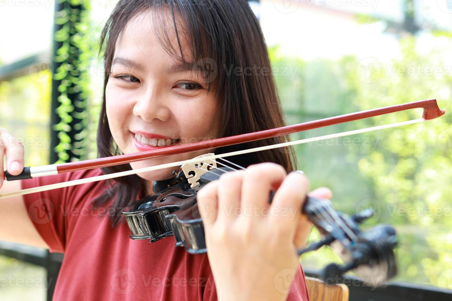 Asian woman playing classical instrument violin at home in the morning. She enjoys playing music. international music education concept Learning and practicing. Band and live music photo