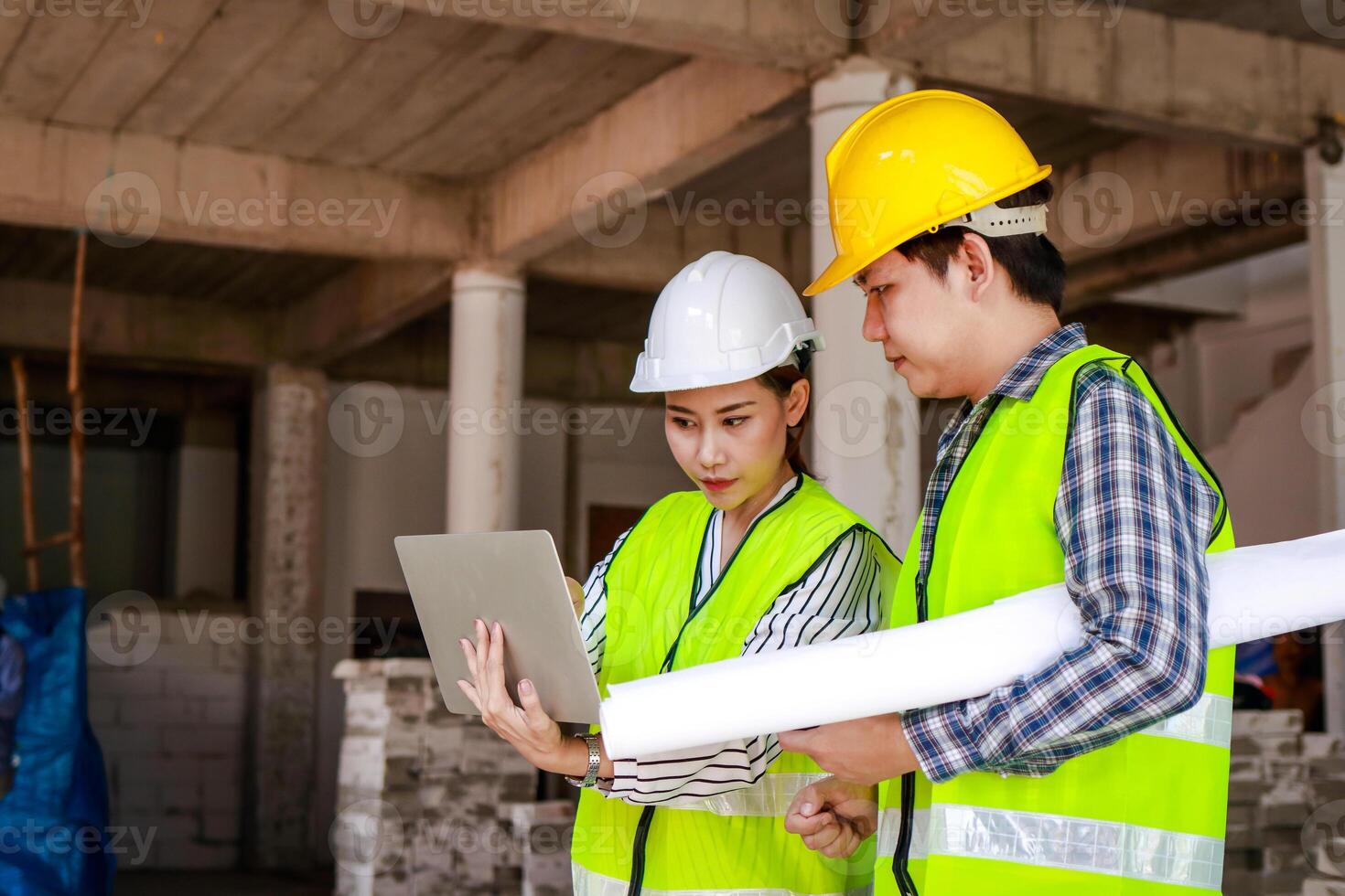 Engineers and construction contractors Holding a laptop to discuss building construction plans at the outdoor site. Real estate project concepts, building construction cooperation. photo