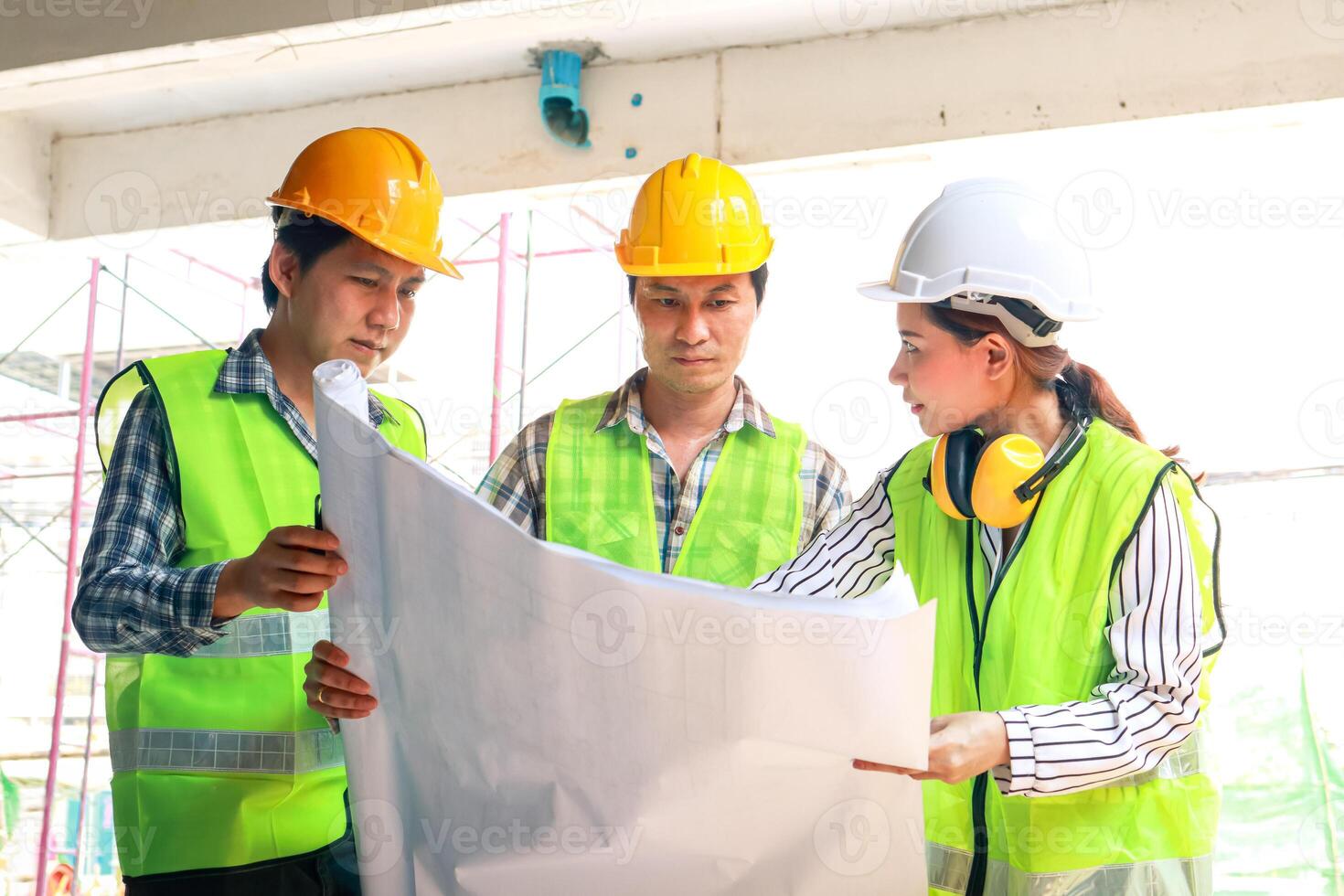 Architects and Engineers and Builders Holding a blueprint discussing building construction plans at the outdoor site. Real estate project concepts, building construction cooperation. photo