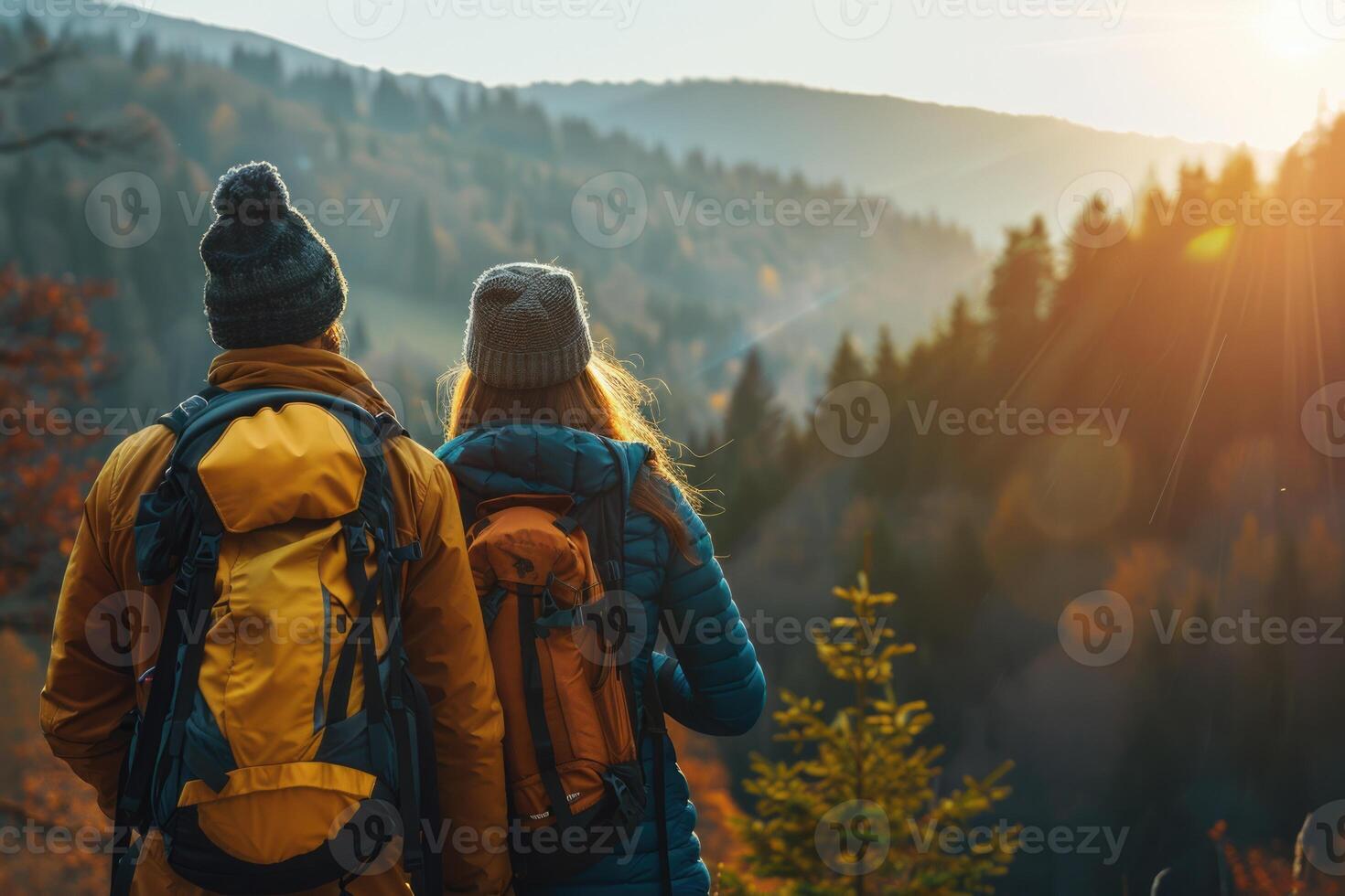 A young couple of travelers stands on a hill and watches the sunrise. Hiking concept photo