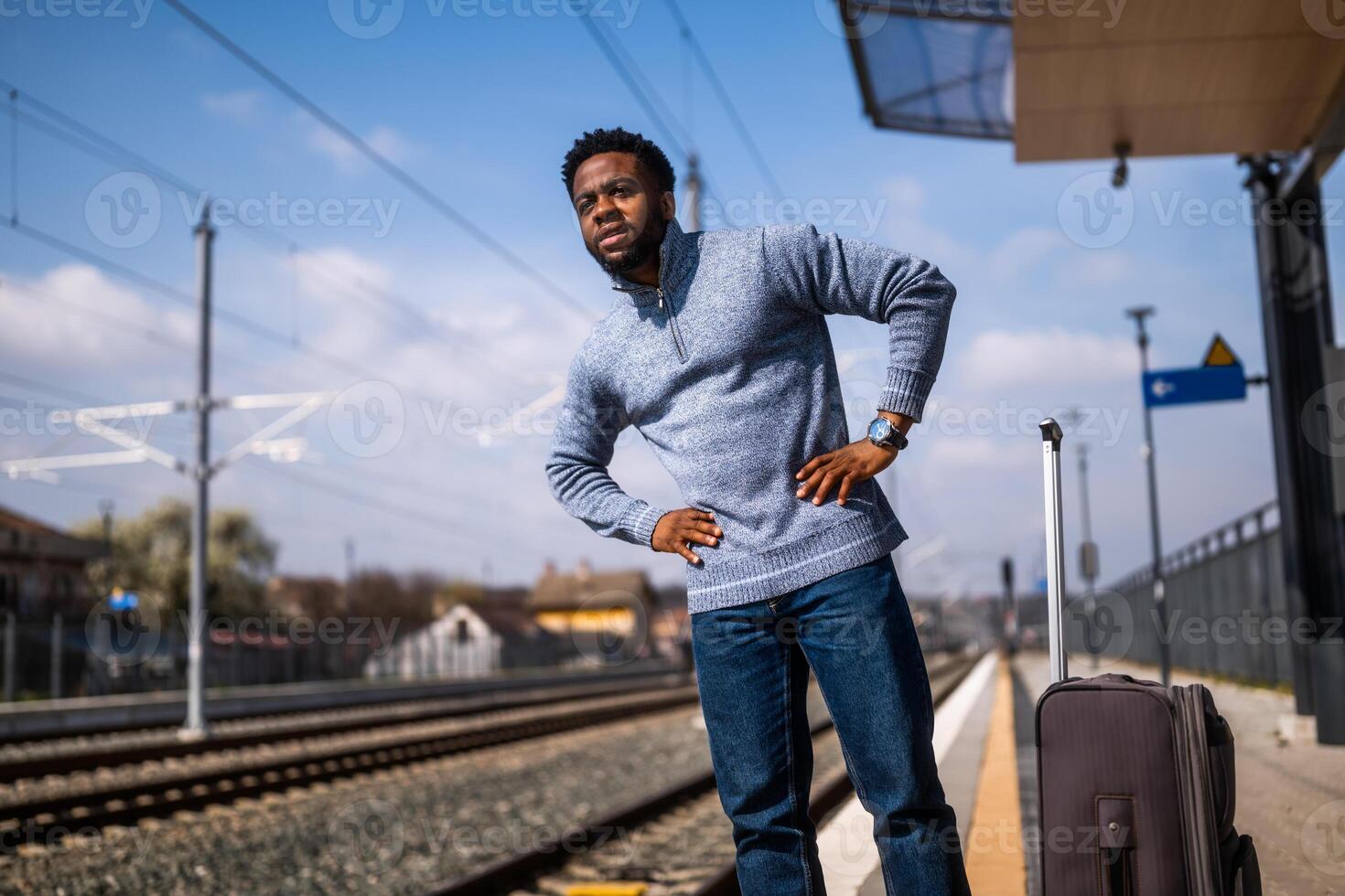 Worried man with a suitcase standing on a railway station. photo