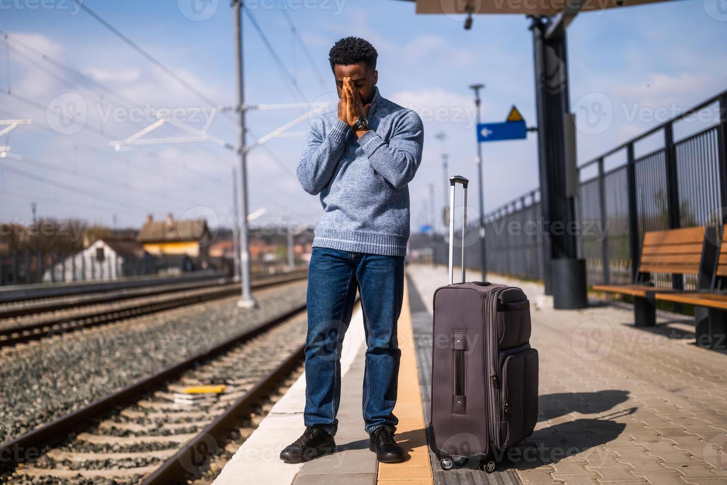 Worried man with a suitcase standing on a railway station. photo