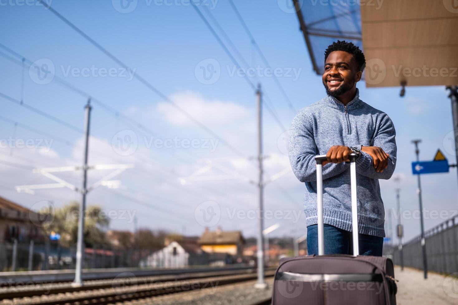 contento hombre con maleta en pie en ferrocarril estación foto