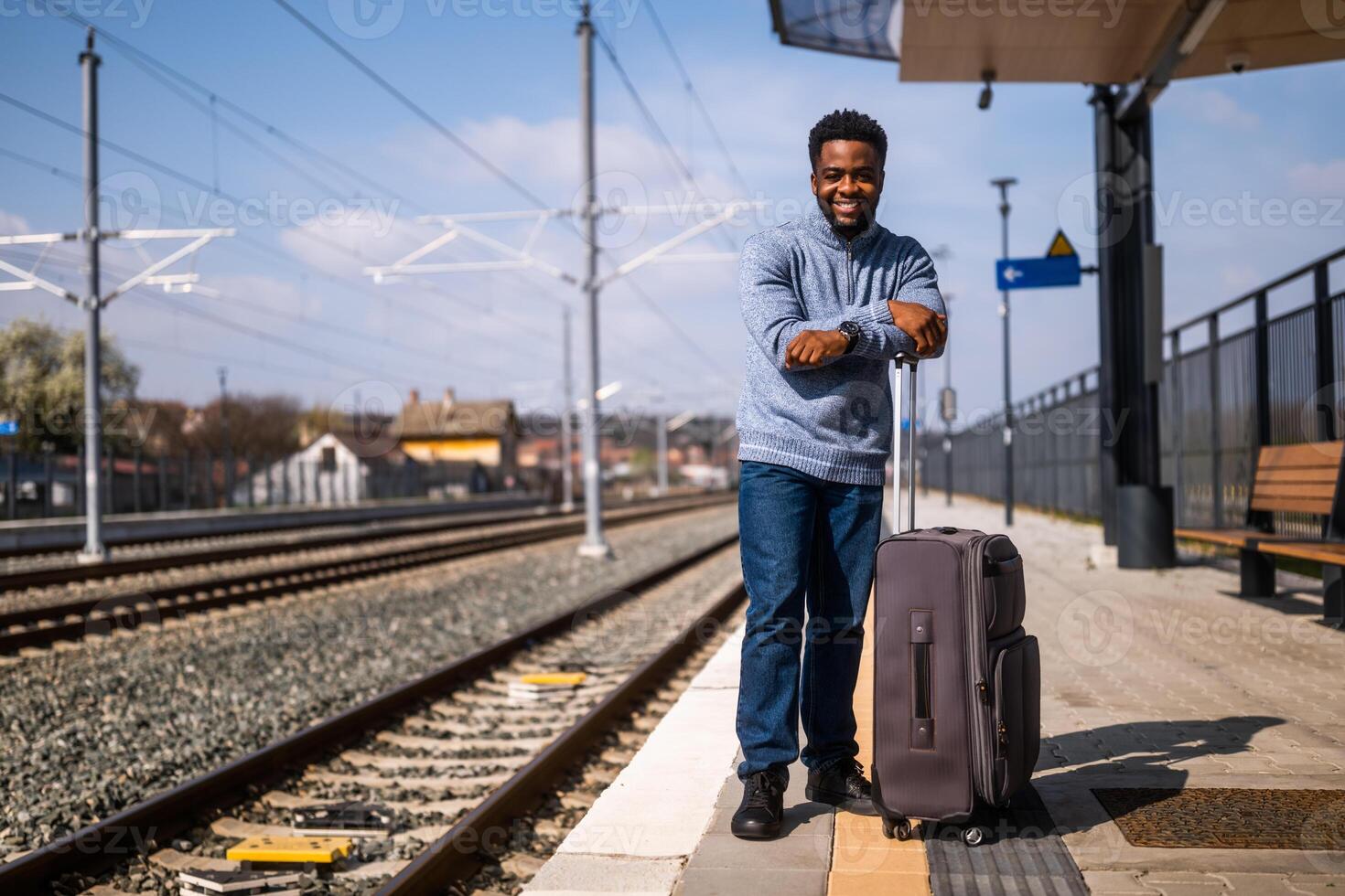 Happy man with suitcase standing on railway station photo