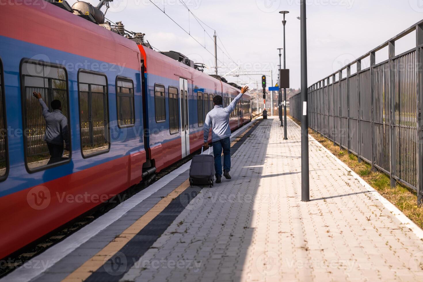 hombre ondulación a un dejando tren y corriendo a lo largo ferrocarril estación con maleta. foto