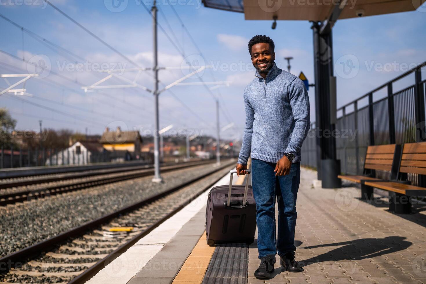 Happy man with suitcase walking on railway station. photo