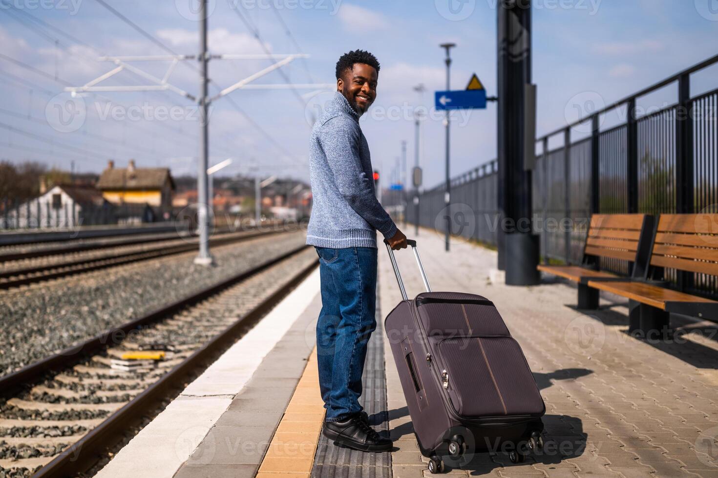 Happy man with suitcase standing on railway station. photo