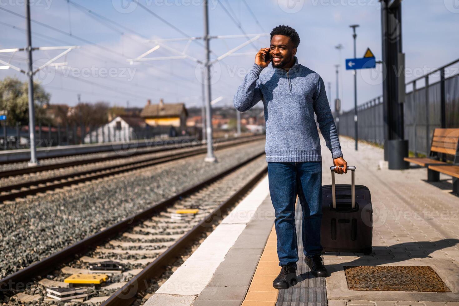 contento hombre con un maleta es hablando en el teléfono mientras caminando en el ferrocarril estación. foto