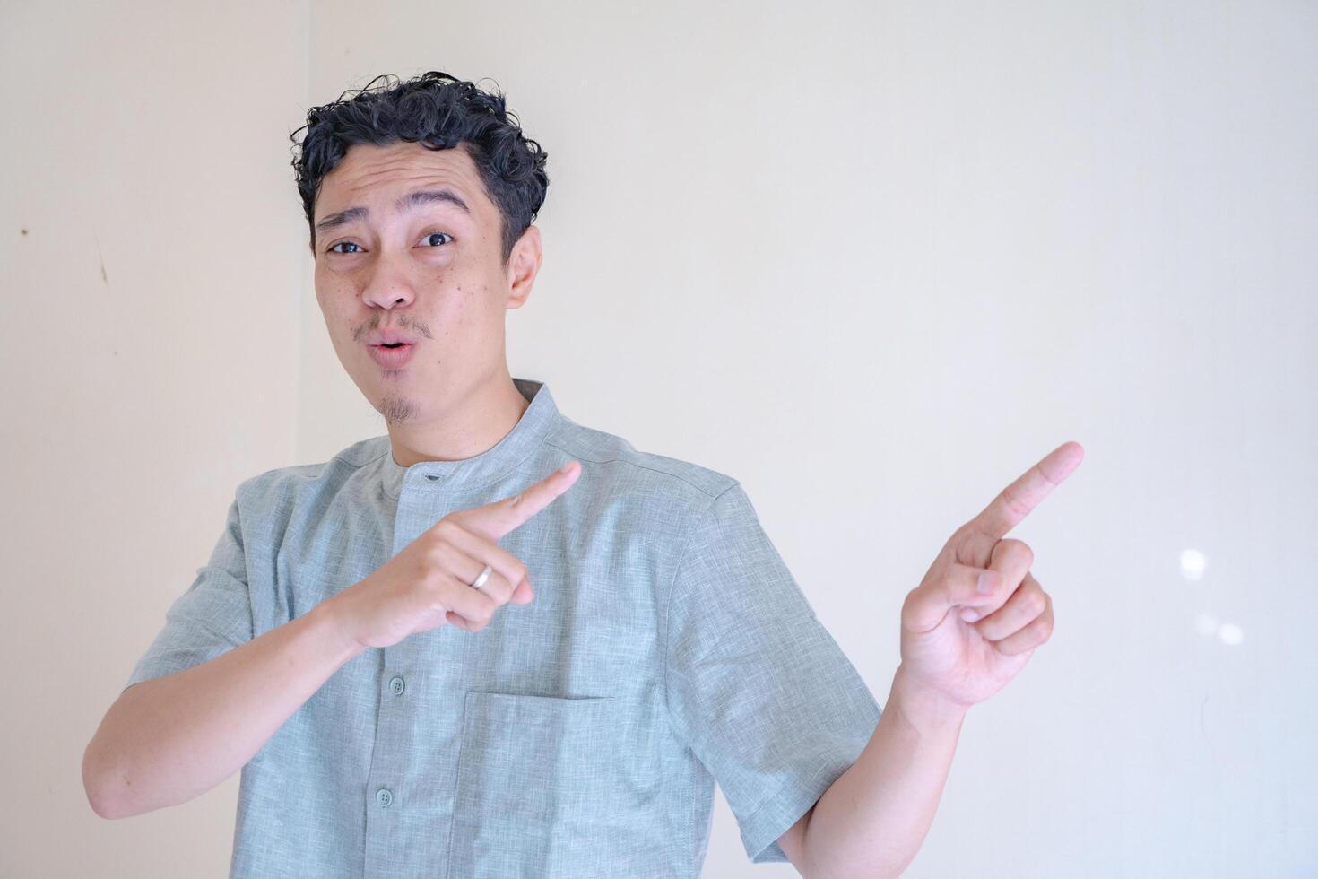 Moslem Asian man pointing the link gesture when Ramadan celebration. The photo is suitable to use for Ramadhan poster and Muslim content media.