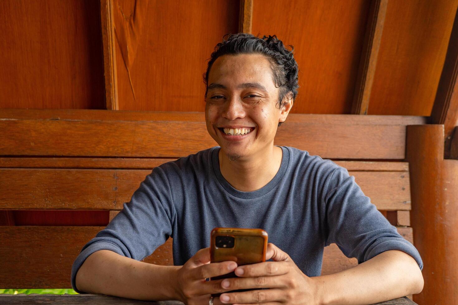 Man smile happy and surprised when looking at phone on the restaurant. The photo is suitable to use for expression advertising and ecommerce.