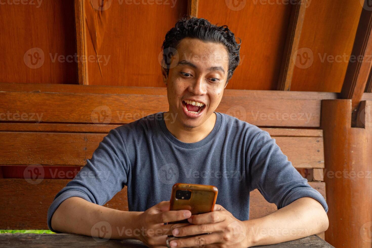 Man smile happy and surprised when looking at phone on the restaurant. photo