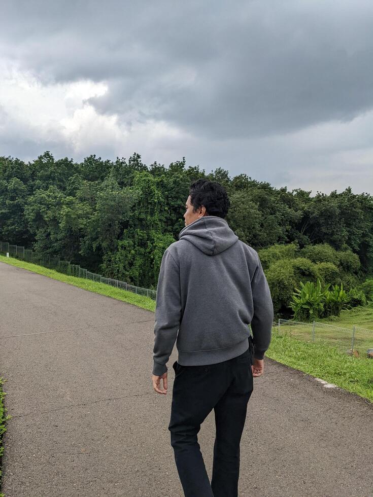Man walking on the park when day time. The photo is suitable to use for calm enjoyed activity, leisure activity and park background.