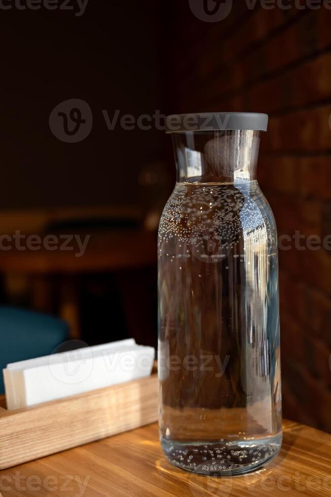bottle of water on a wooden table against the background of a brick wall in a cafe, close-up photo