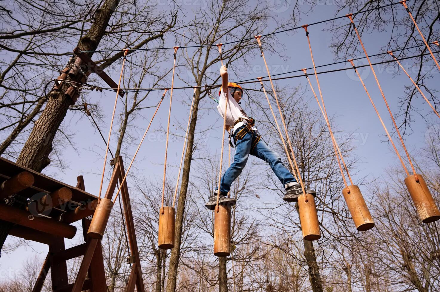 un chico en un casco sube un cuerda parque en el primavera foto