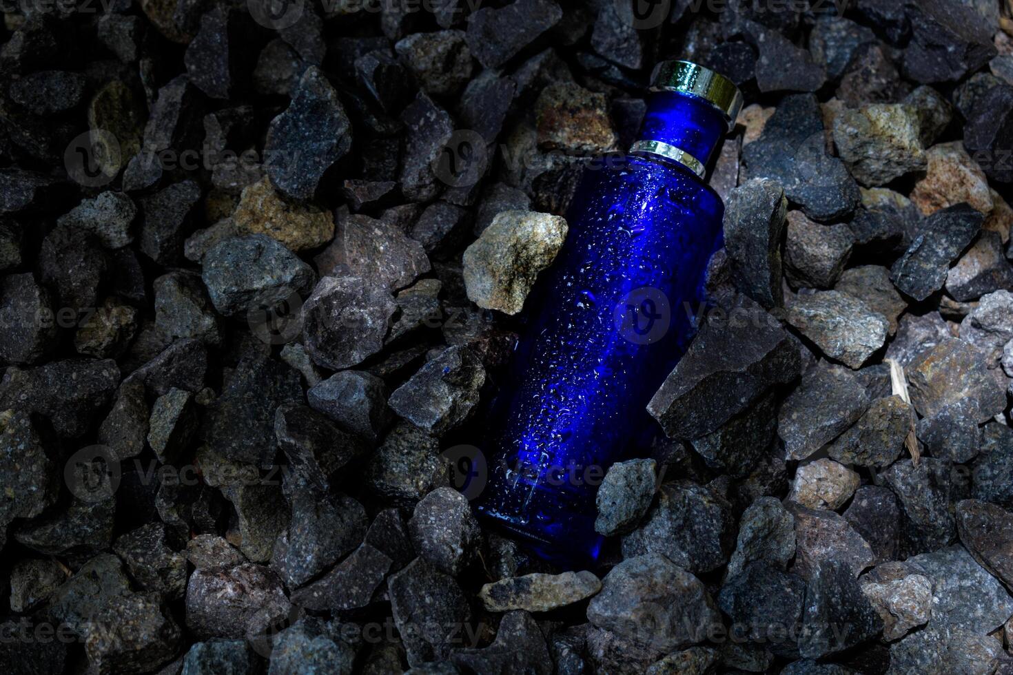 perfume oscuro azul transparente botella en grava o coral antecedentes foto