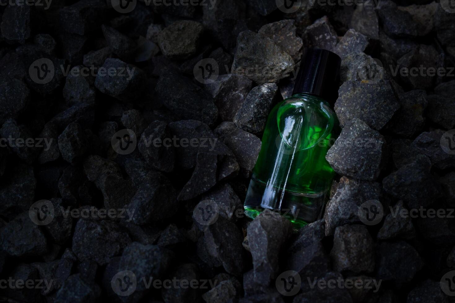 Perfume green transparent bottle in gravel or coral background photo