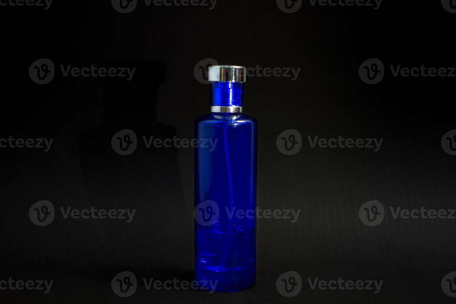 Transparent Dark Blue Bottle Perfume isolated black background for mock up design photo