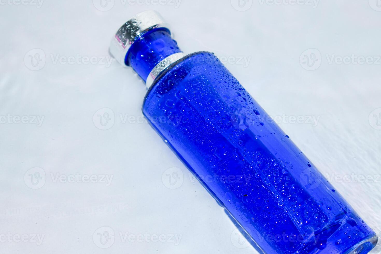 Perfume Dark Blue transparent bottle in water background photo