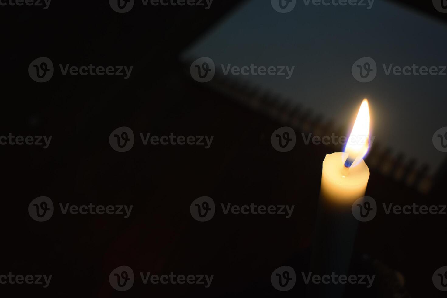 Single Candle with flame in the dark place with book blur background photo