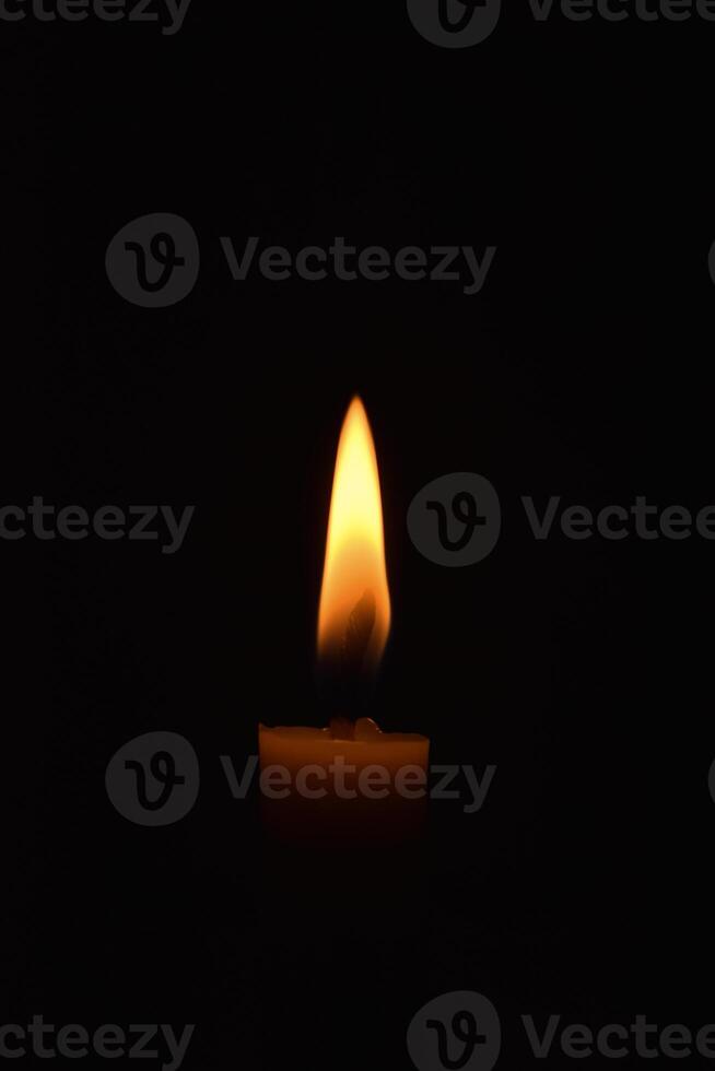 Single Candle with flame in the dark place, isolated black background photo