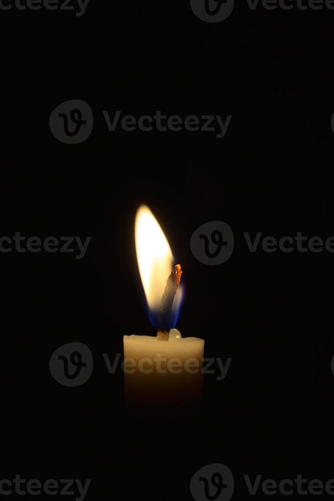 Single Candle with flame in the dark place, isolated black background photo