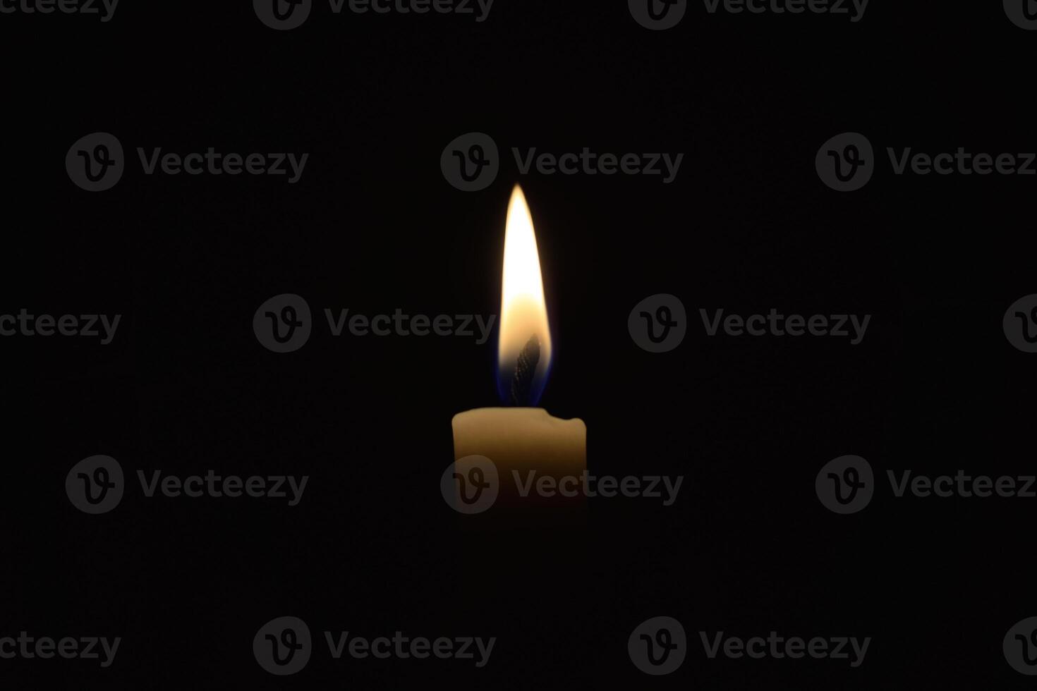 Single Candle with flame in the dark place, isolated black background photo