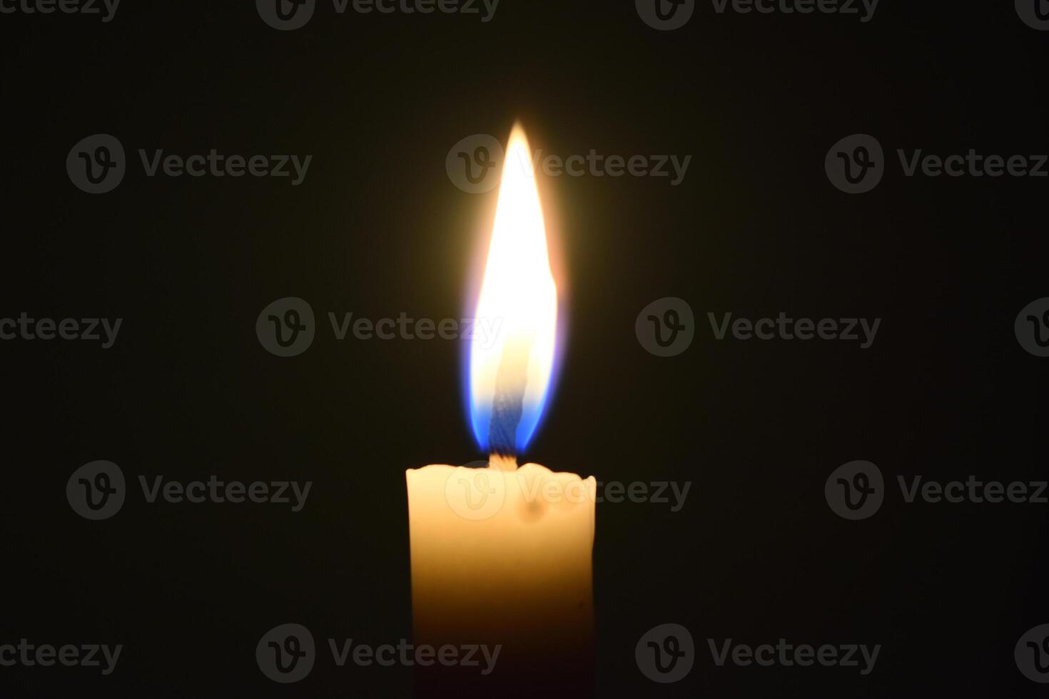 Single Candle with flame in the dark place, isolated black background photo