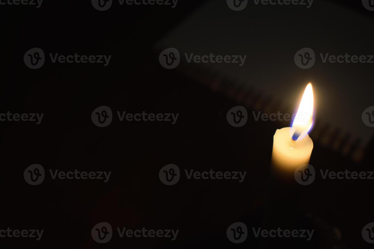 Single Candle with flame in the dark place with book blur background photo