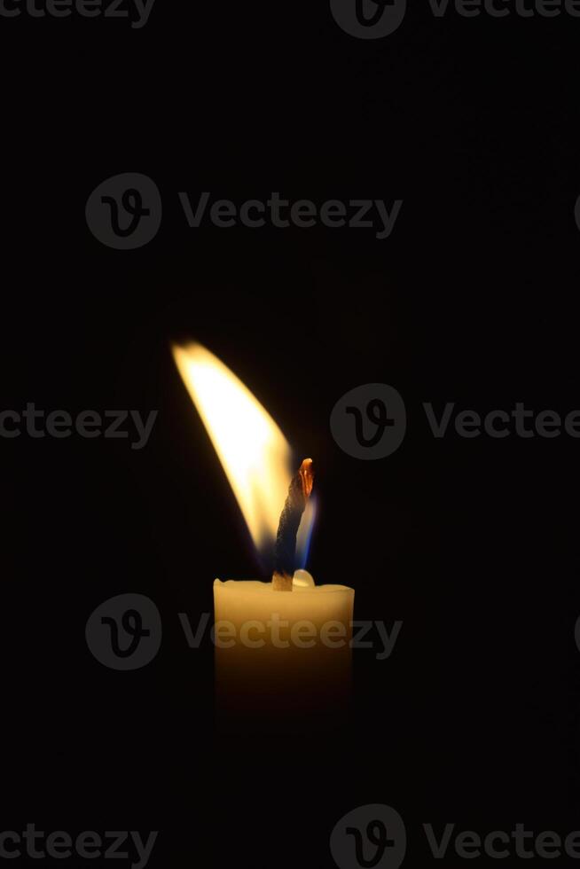 Single Candle with flame in the dark place, isolated black background photo