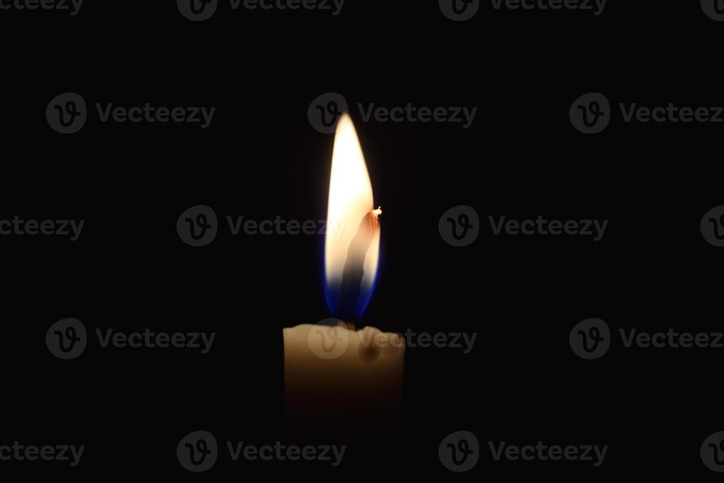 Single Candle with flame in the dark place, isolated black background photo