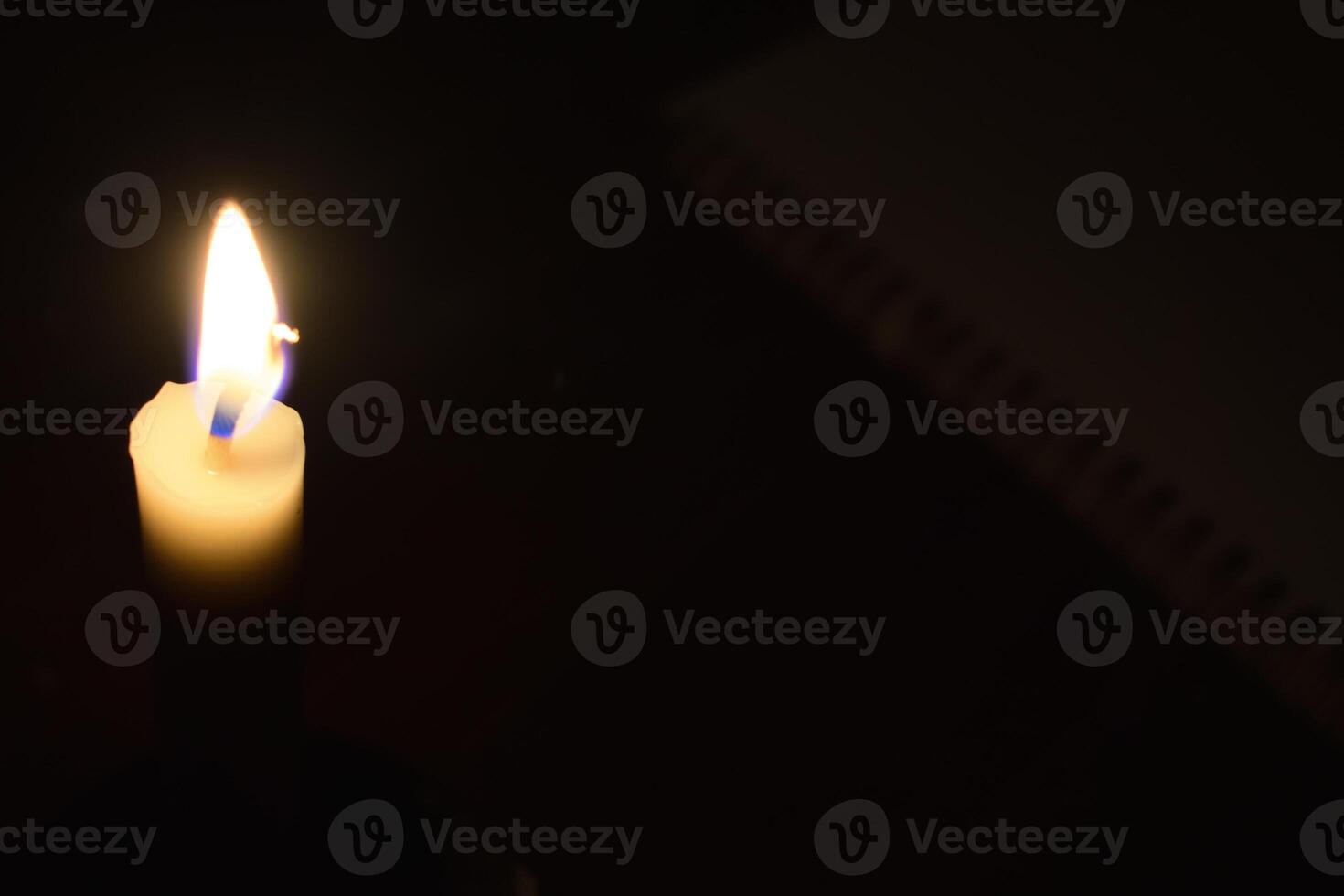 Single Candle with flame in the dark place, isolated black background photo