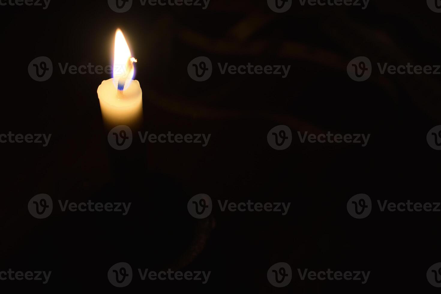 Single Candle with flame in the dark place, isolated black background photo