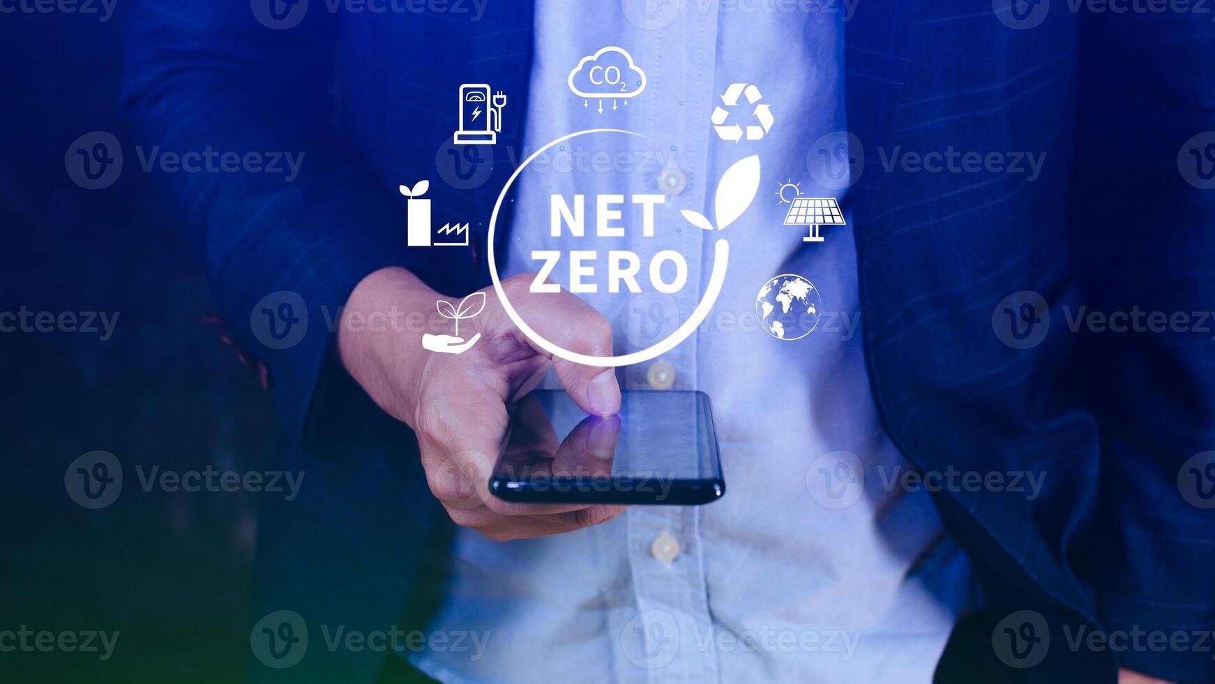 Net Zero and Carbon Neutral Concepts, Net zero greenhouse gas emissions target, Climate neutral long strategy, Businessman holding NetZero icon with smartphone. photo