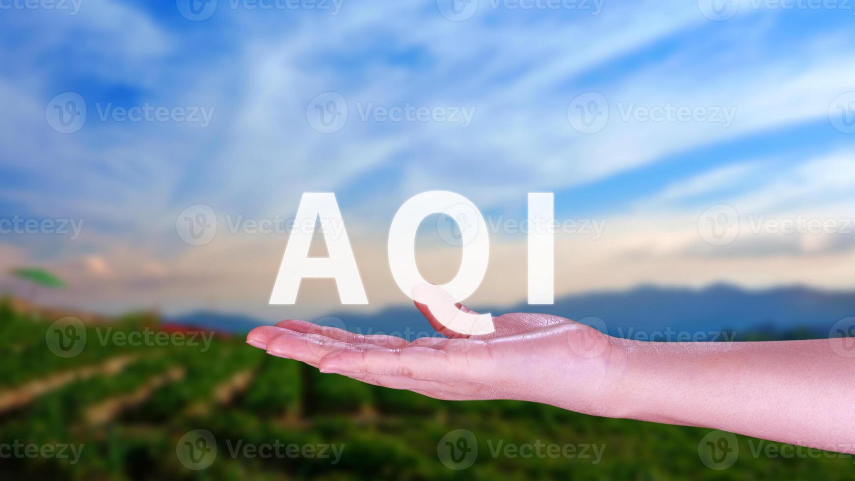 AQI, Abbreviation of air quality index, hand holding AQI on nature background, environment concept. photo
