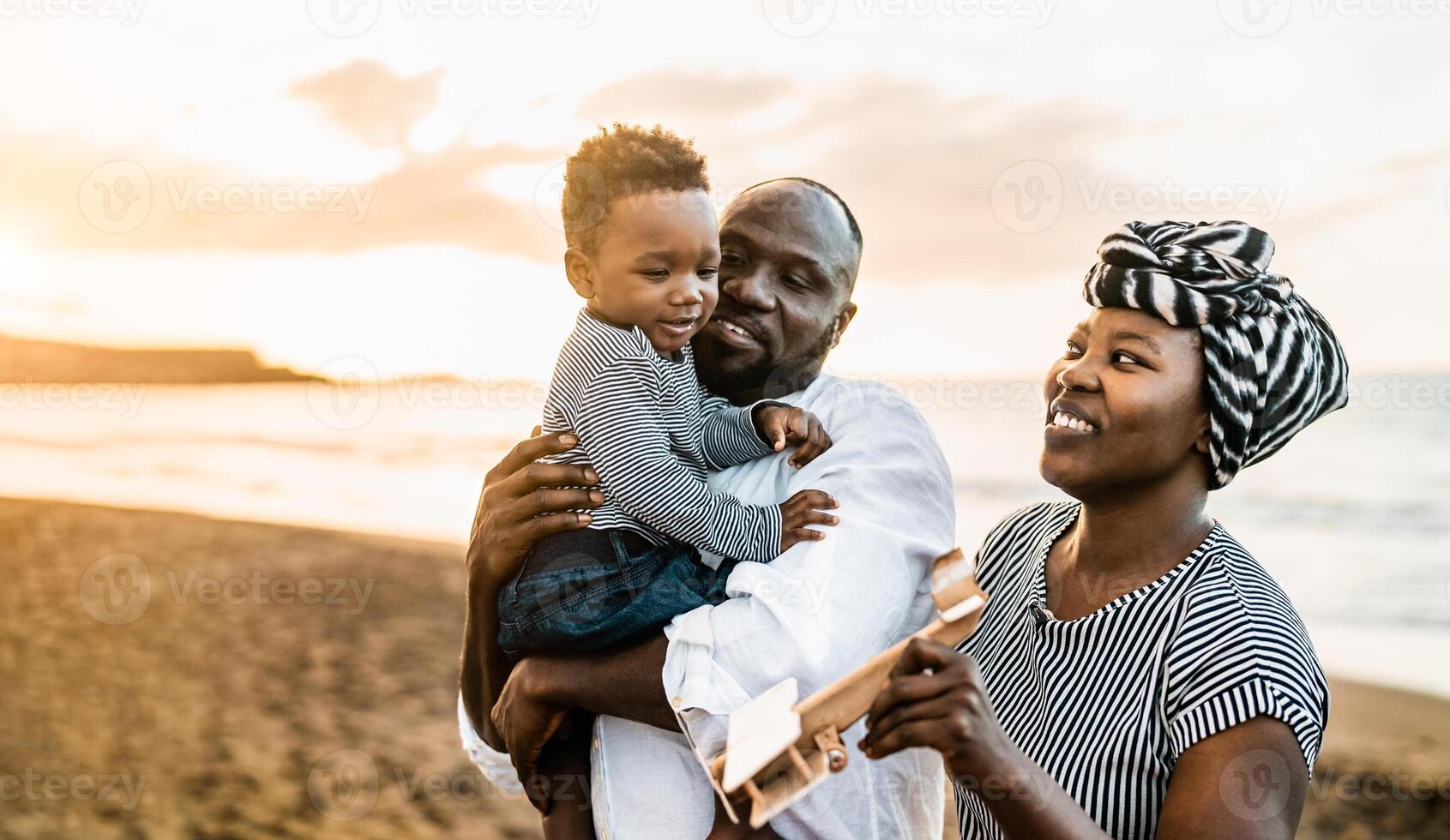 Happy African family having fun on the beach during summer vacations photo