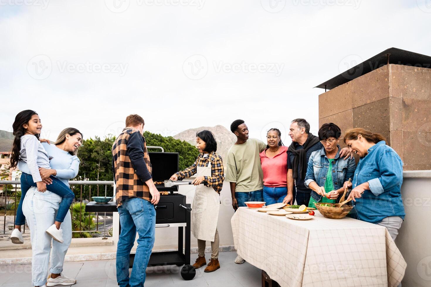 multigeneracional amigos teniendo divertido haciendo parilla a casa techo - contento multirracial personas Cocinando juntos foto