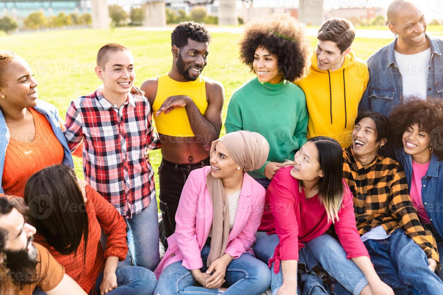 Happy young multiracial people having fun sitting on grass in a public park - Diversity and friendship concept photo