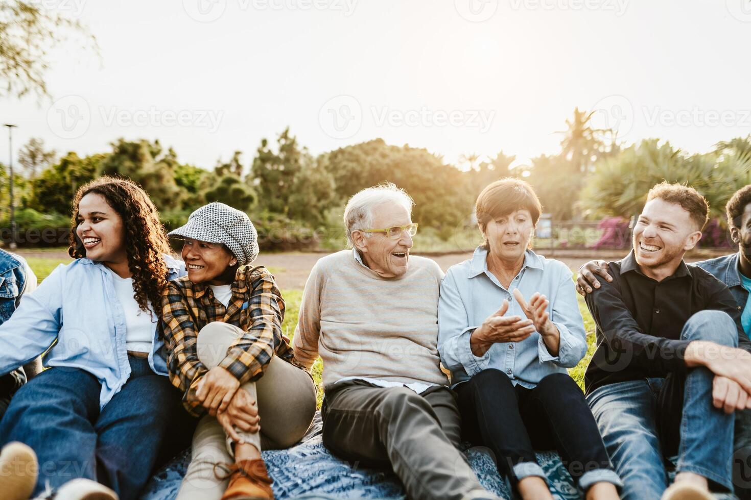 contento multi generacional personas teniendo divertido sentado en césped en un público parque - diversidad y amistad concepto foto