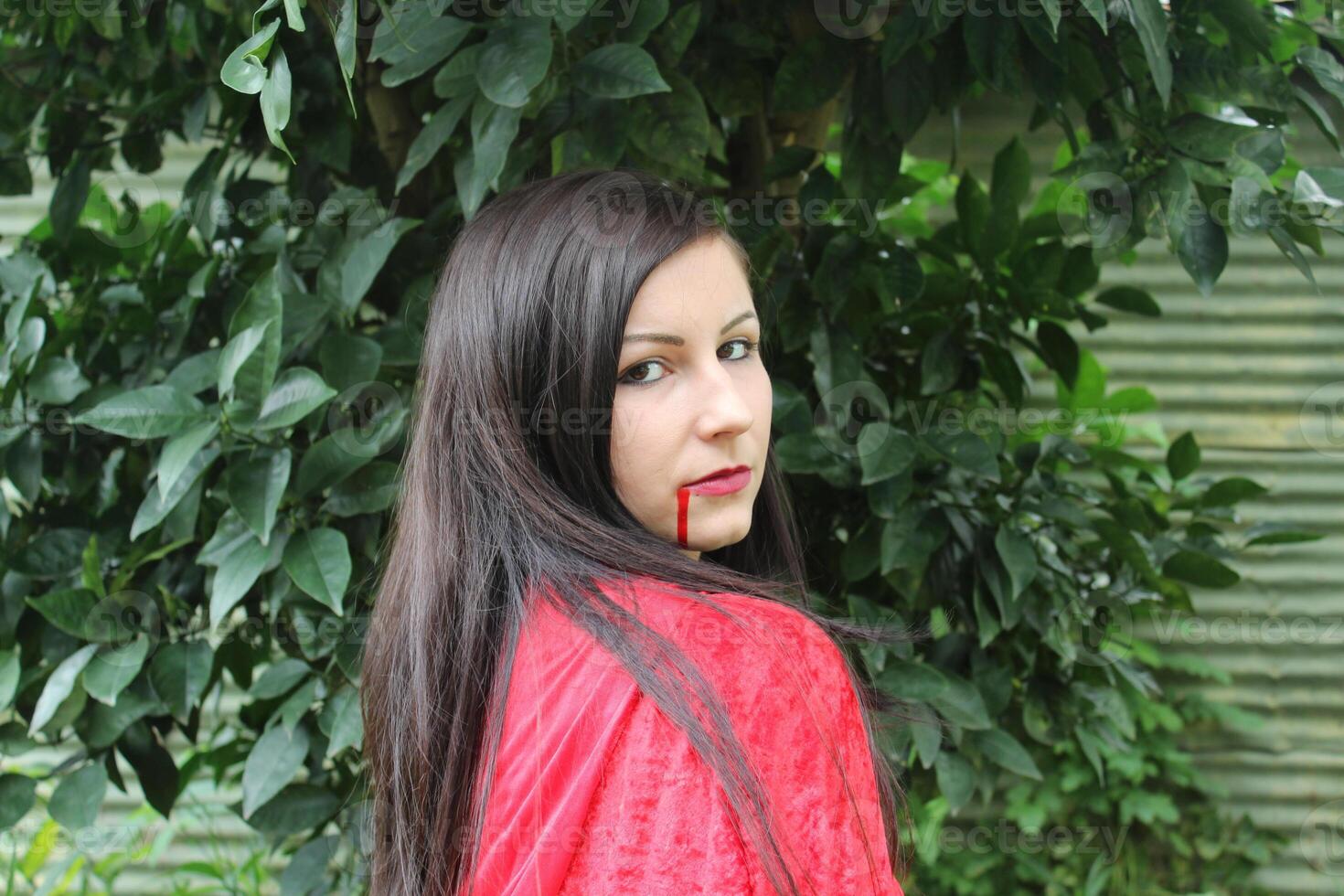 A Vampire Woman in a Red Cape with a Bloody Mouth. photo