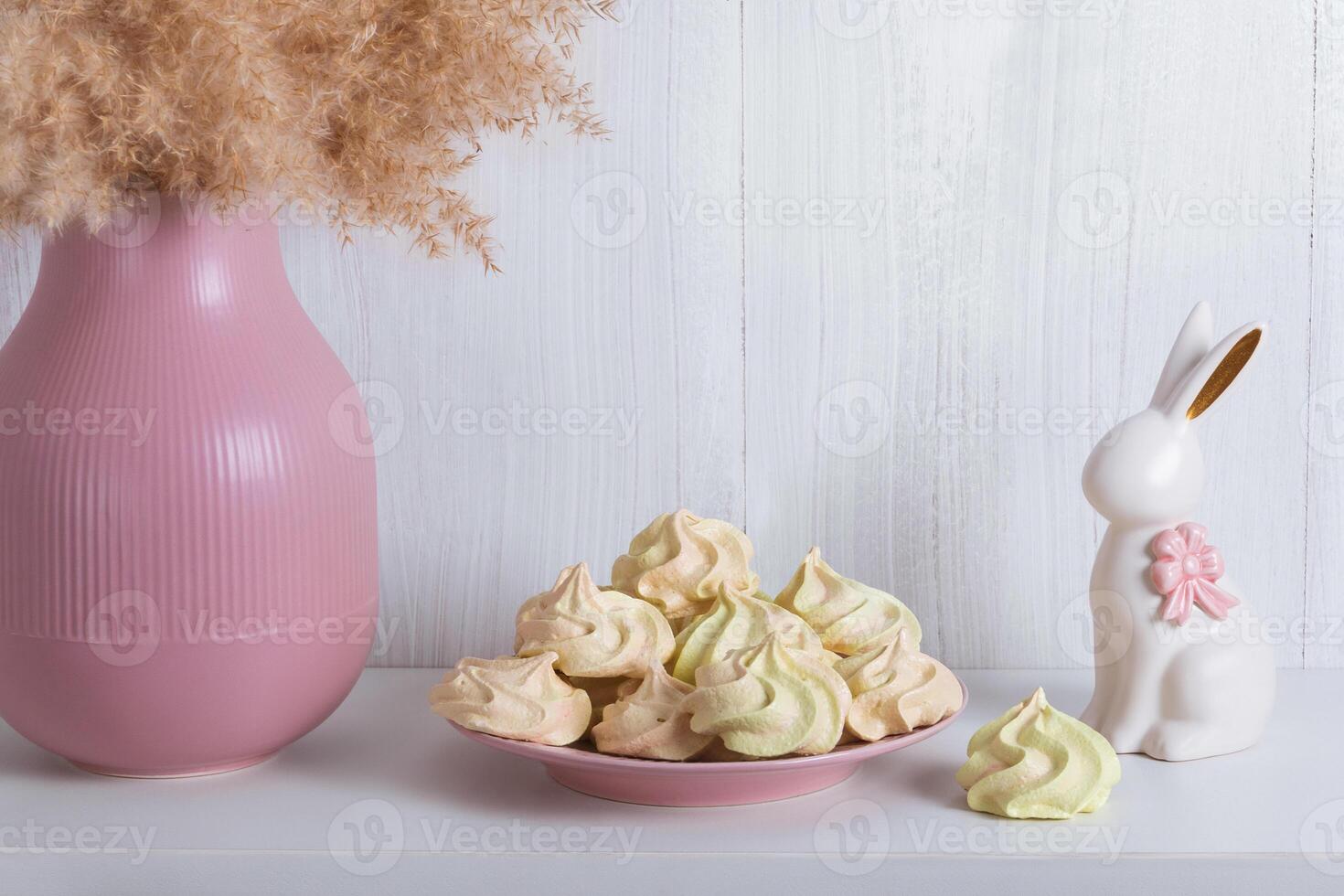 Festive light card with a porcelain rabbit, meringue and a pink vase with copy space photo