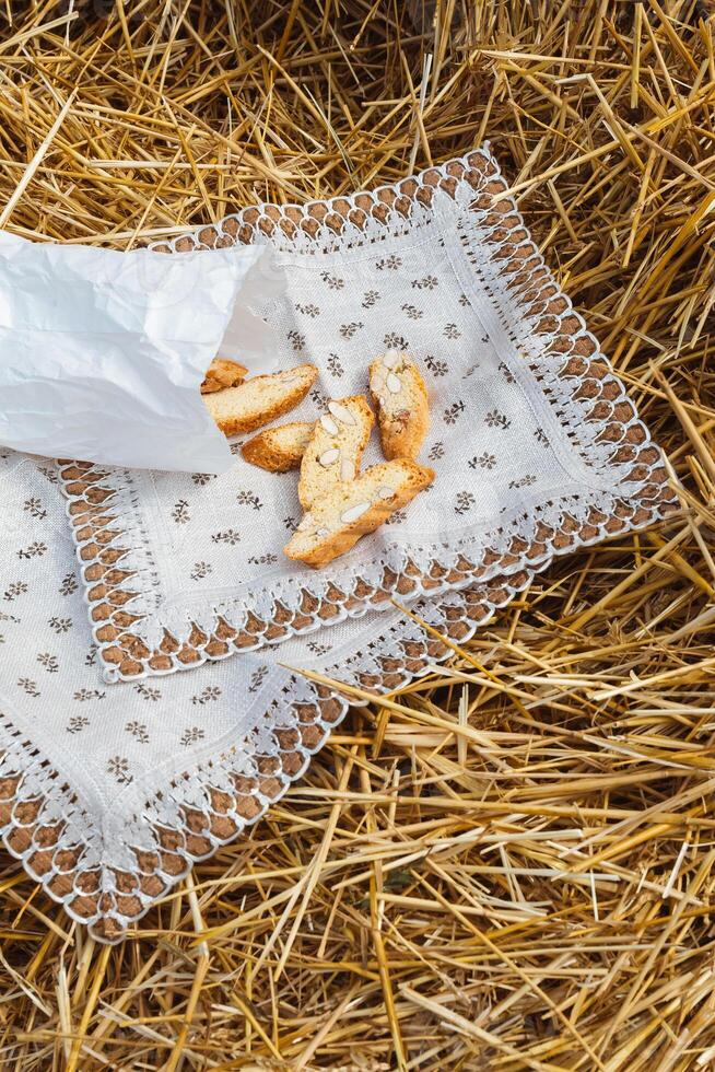 Almond cookies crackers with pieces of nuts lie on a napkin against the background of straw. A snack in nature photo