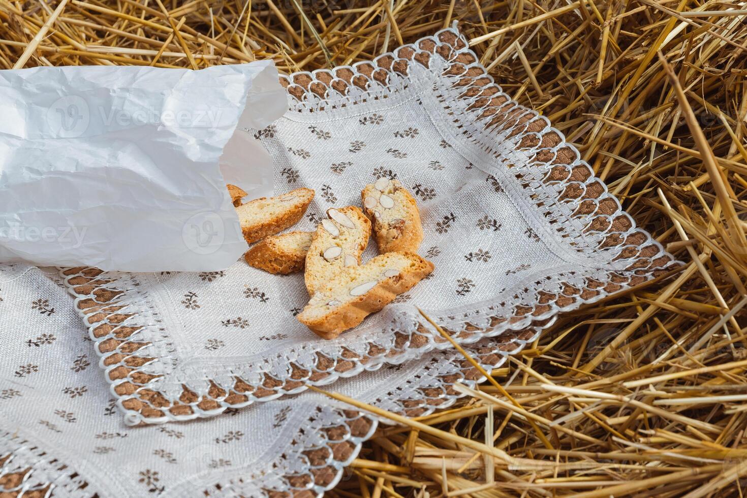 Almond cookies crackers with pieces of nuts fell out of a paper bag on a napkin lying on the straw photo