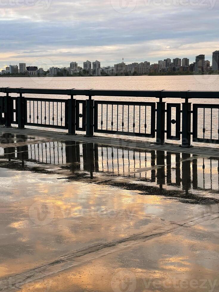 puesta de sol en el terraplén después el lluvia. reflexión de el cielo en el mojado acera, kazán, Rusia foto