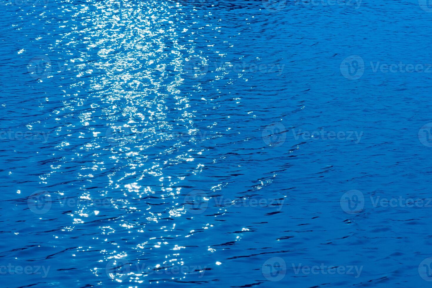 Bluewater waves on the surface ripples blurred. Defocus blurred transparent blue colored clear calm water surface texture with splash and bubbles. Water waves with shining pattern texture background. photo